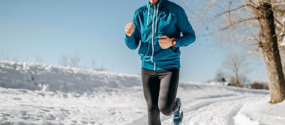 man running in snow with blue vest and black joggings