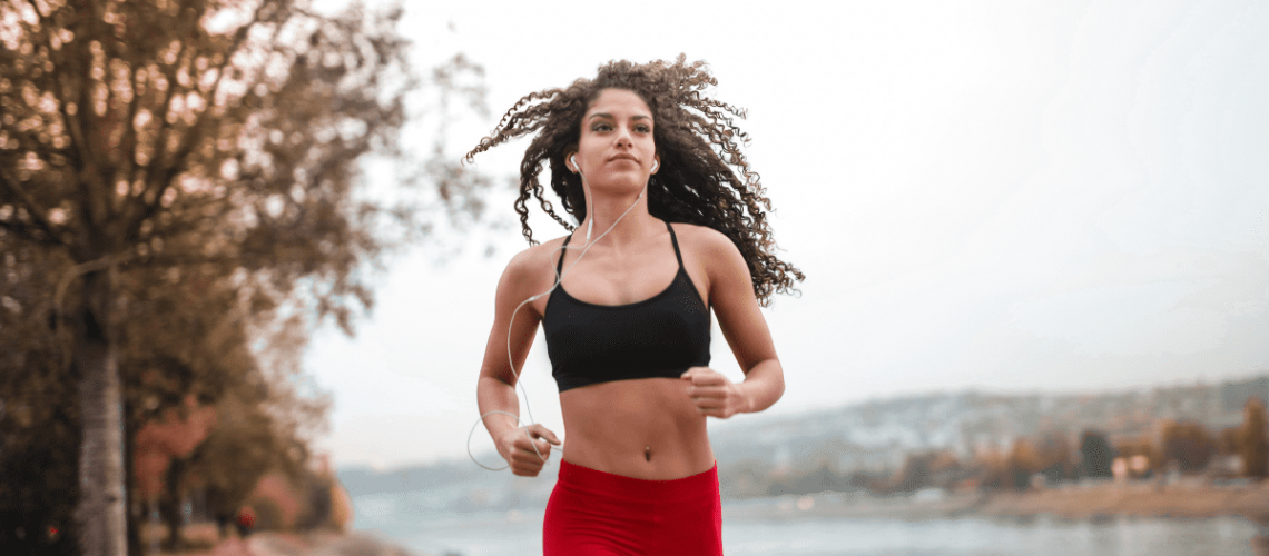 Curly woman in black top and red leggings running outdoors, curly hair